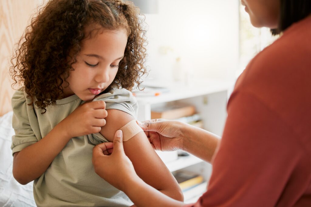 Young child having plaster put on arm following a vaccination