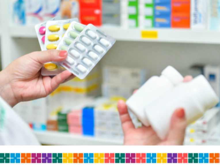 A person holding some blister packs and plastic containers showing different types of medication