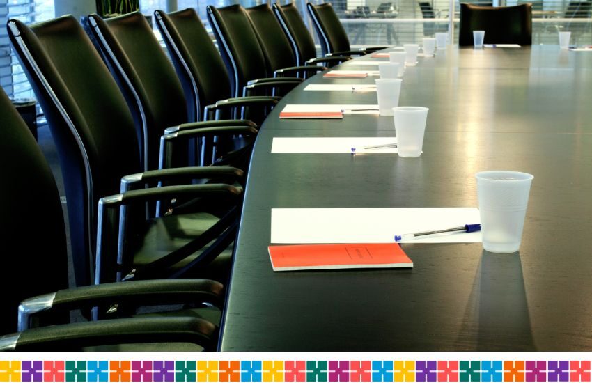 able with office chairs. The table has notepads, pens and plastic cups for water.