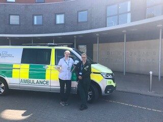 The west Essex falls car (ambulance) parked in front of St Margaret's Hospital in Epping. There are two health care professionals stood in front of the car