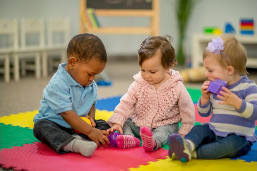 Three toddlers sitting and playing at a nursery