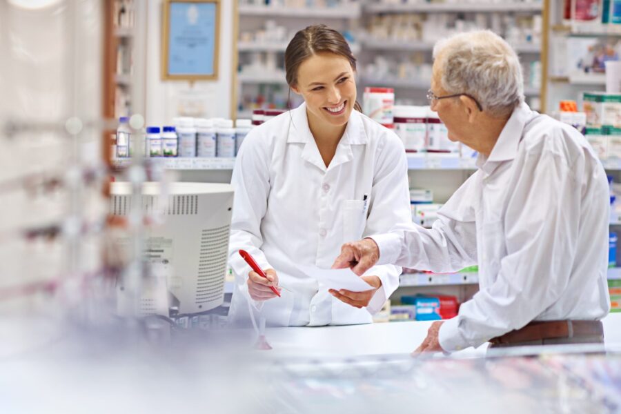 Pharmacist with an older male customer, who is pointing at a piece of paper